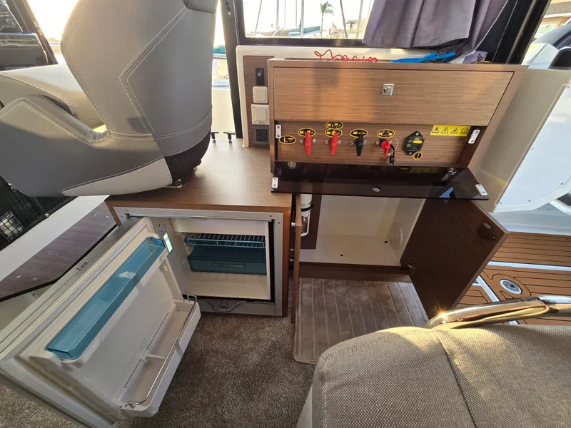 Slide: The Image of 2020 Jeanneau NC 895 Sport interior with control panel and open mini fridge. - 31