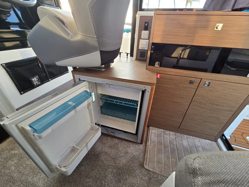 Slide: The Image of 2020 Jeanneau NC 895 Sport interior with open fridge and wooden cabinetry. - 36