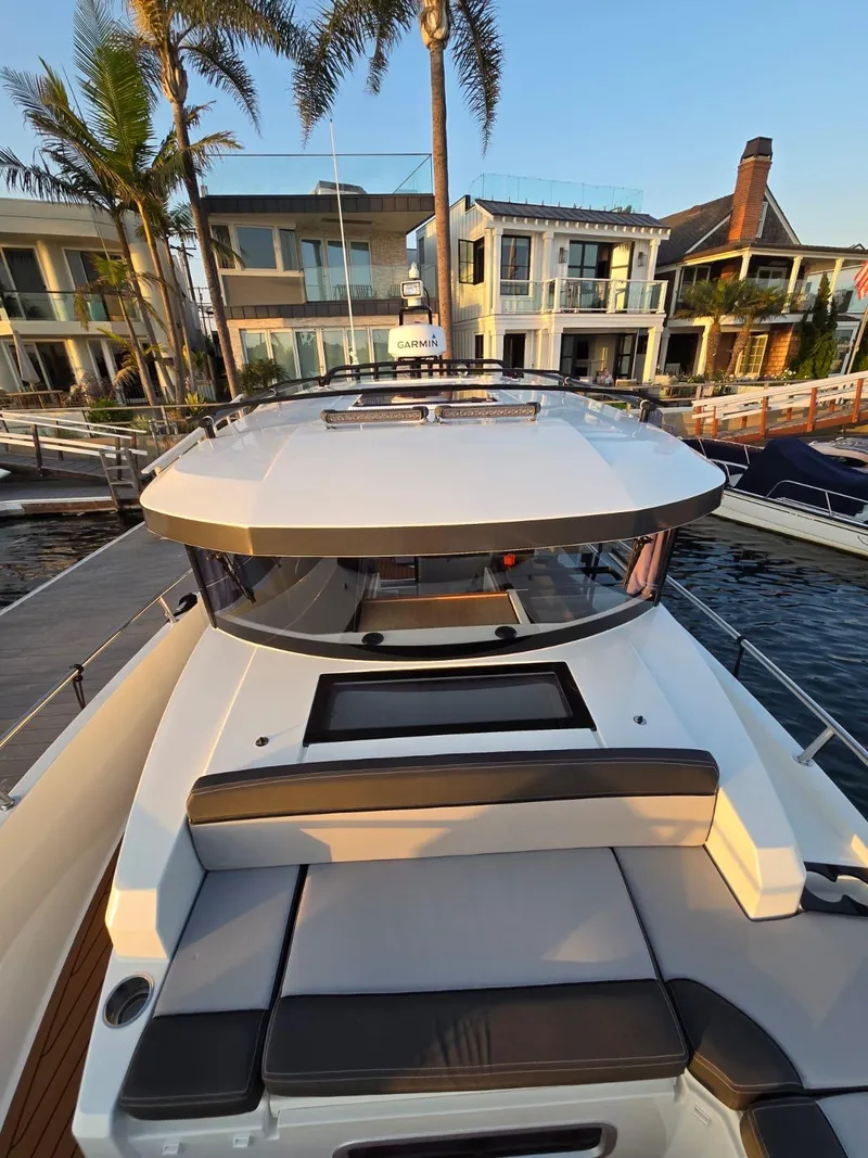 Slide: The Image of 2020 Jeanneau NC 895 Sport boat docked near modern waterfront homes. - 48