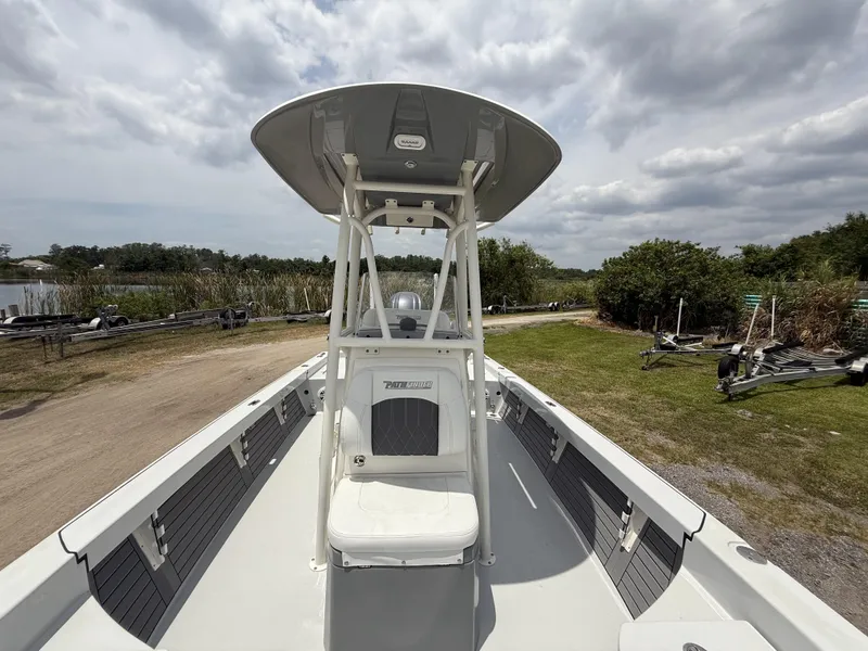 Slide: The Image of 2024 Pathfinder 2600 HPS boat on land, under cloudy sky, near water and greenery. - 32