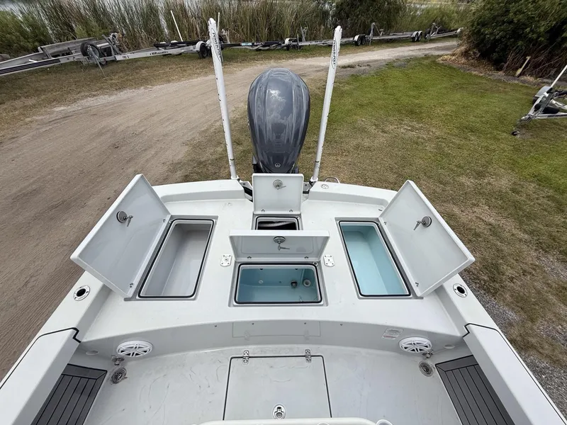 Slide: The Image of 2024 Pathfinder 2600 HPS boat with open storage compartments and motor, parked on grass. - 35