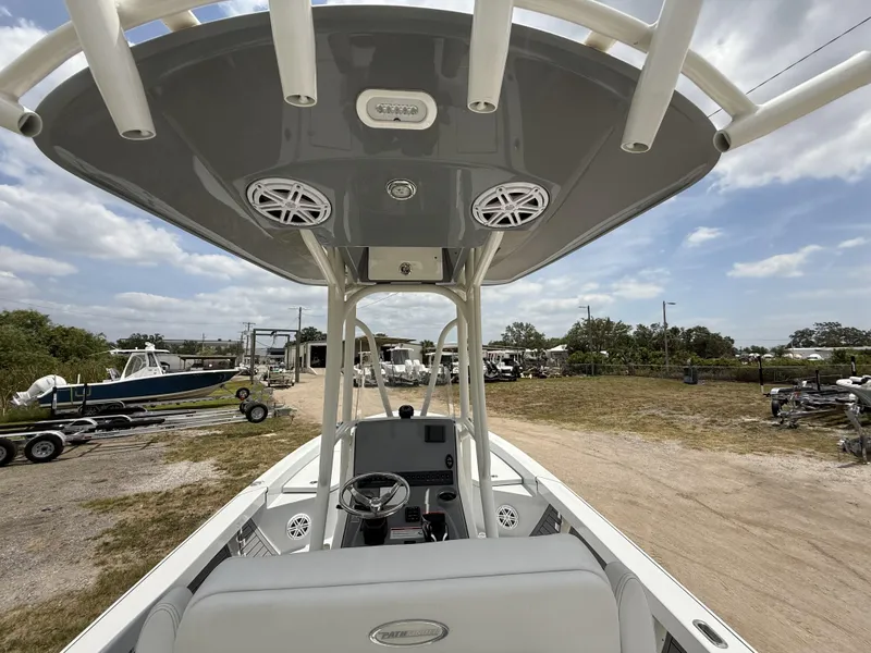 Slide: The Image of 2024 Pathfinder 2600 HPS boat interior with T-top and steering console, parked outdoors. - 8