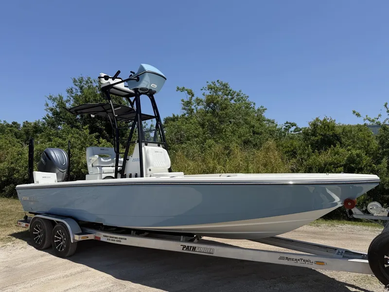 Slide: The Image of 2024 Pathfinder 2500 Hybrid boat on trailer, parked outdoors, clear sky background. - 1
