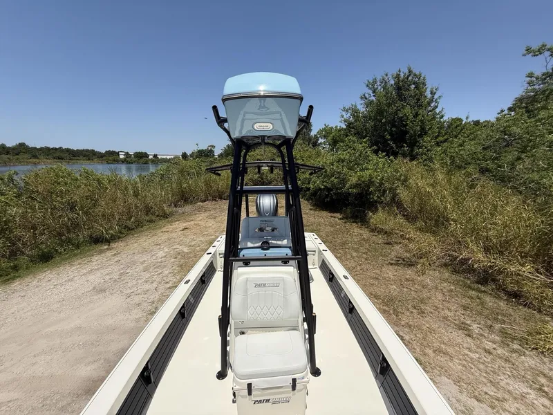 Slide: The Image of 2024 Pathfinder 2500 Hybrid boat on a grassy shore near a lake. - 13