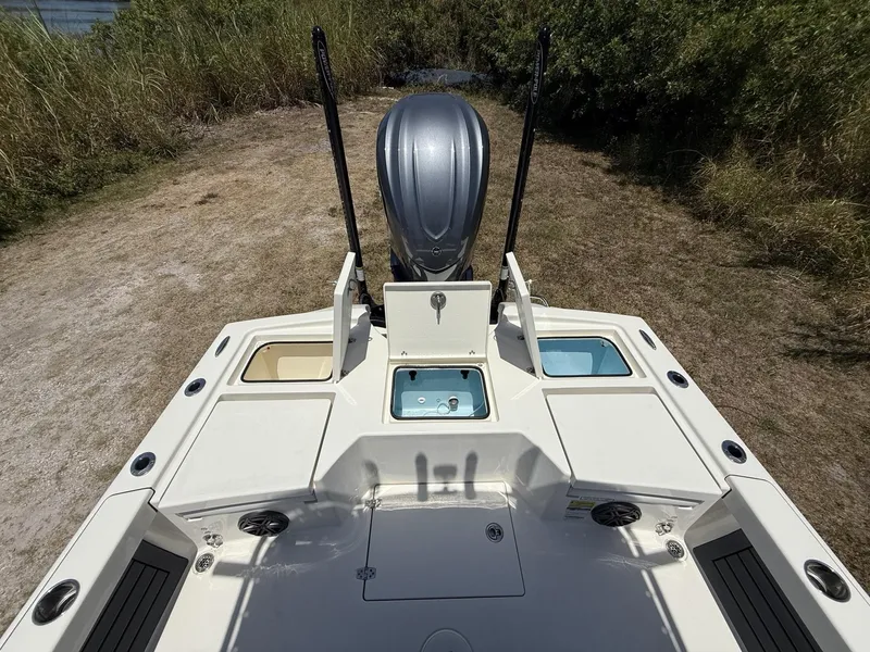 Slide: The Image of 2024 Pathfinder 2500 Hybrid boat deck with storage compartments and motor, surrounded by grass. - 16