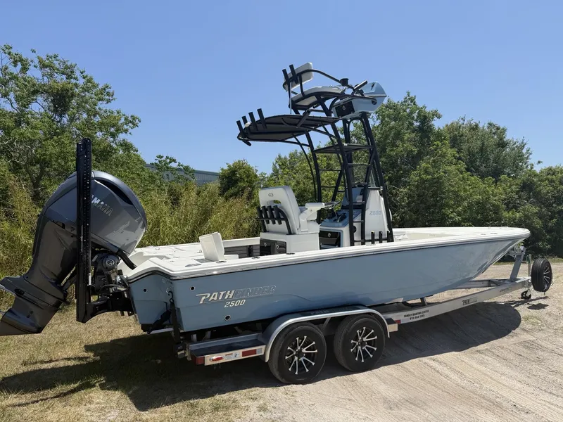 Slide: The Image of 2024 Pathfinder 2500 Hybrid boat on trailer, parked outdoors with trees in background. - 2