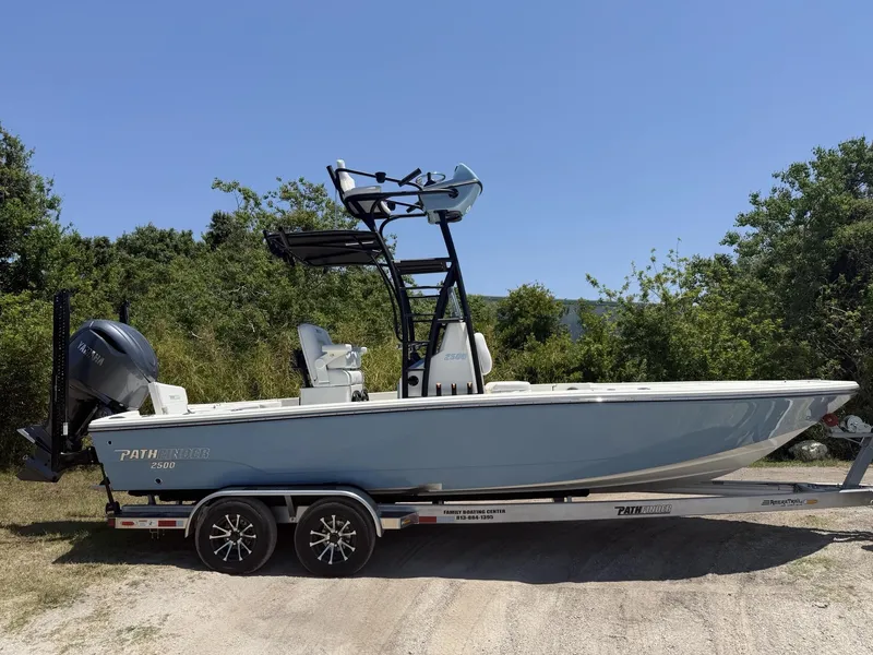 Slide: The Image of 2024 Pathfinder 2500 Hybrid boat on trailer, parked outdoors, with trees in the background. - 27
