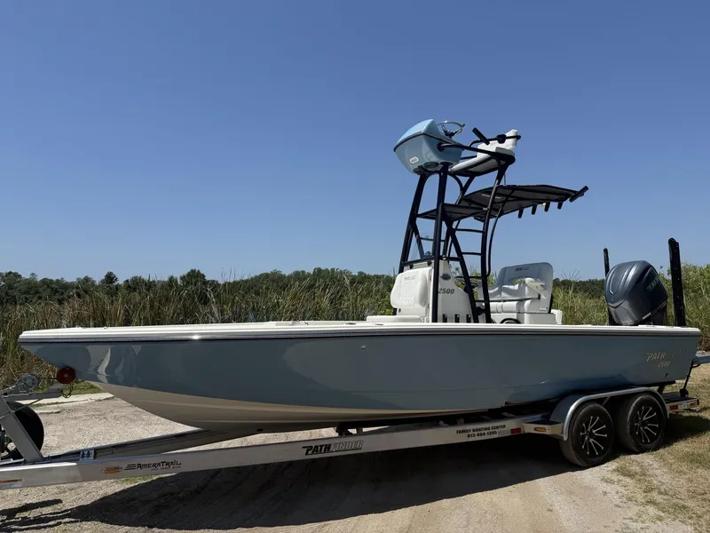 Slide: The Image of 2024 Pathfinder 2500 Hybrid boat on trailer, parked outdoors under clear blue sky. - 30