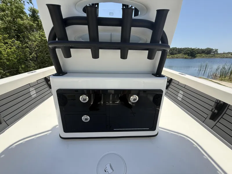 Slide: The Image of 2024 Pathfinder 2500 Hybrid boat interior with rod holders and storage, near a serene lake. - 38
