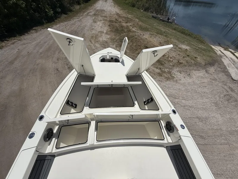 Slide: The Image of 2024 Pathfinder 2500 Hybrid boat with open storage compartments, docked near a lake. - 42