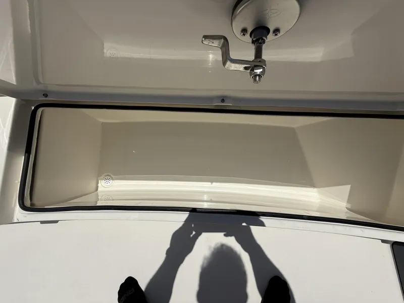 Slide: The Image of Open storage compartment on 2024 Pathfinder 2500 Hybrid boat, featuring a metal latch. - 44