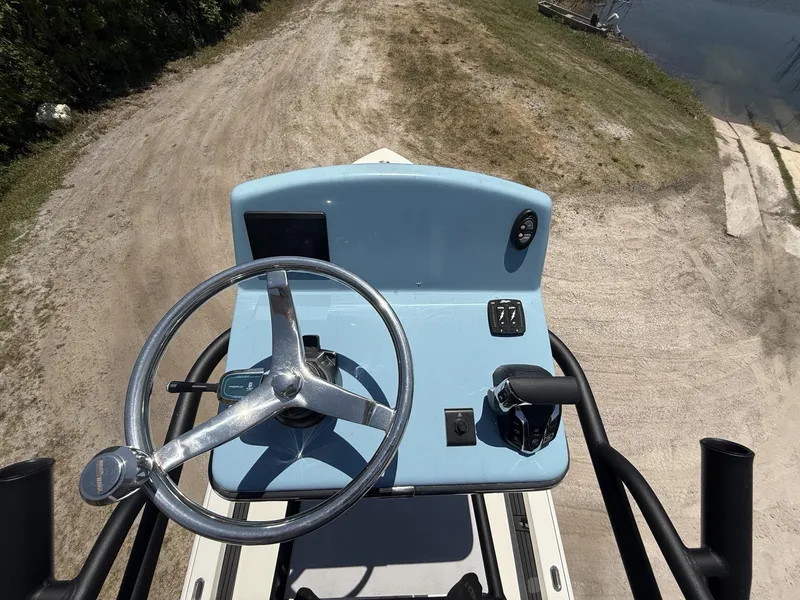 Slide: The Image of 2024 Pathfinder 2500 Hybrid boat console with steering wheel and controls, parked on sandy terrain. - 47
