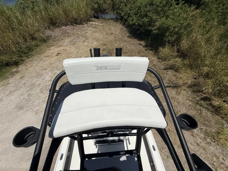Slide: The Image of 2024 Pathfinder 2500 Hybrid boat seat with cup holders, surrounded by grass and dirt path. - 49
