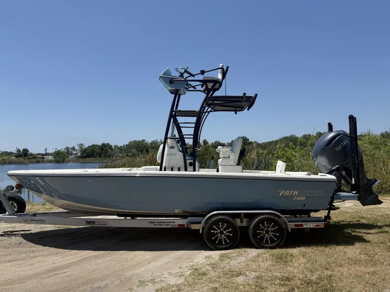 Slide: The Image of 2024 Pathfinder 2500 Hybrid boat on trailer, parked near a lake under clear blue sky. - 6