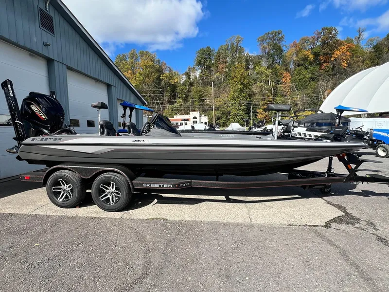Slide: The Image of 2025 Skeeter ZXR 21 boat parked outdoors, showcasing sleek design and dual-axle trailer. - 18