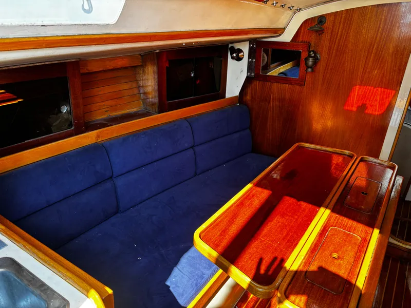 Slide: The Image of Interior of 1982 J Boats 30, featuring blue seating and wooden table. - 10