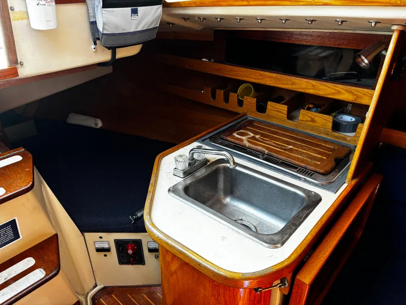 Slide: The Image of 1982 J Boats 30 interior with compact kitchen sink and wooden storage shelves. - 11