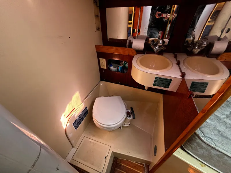 Slide: The Image of 1982 J Boats 30 bathroom with toilet, dual sinks, and mirrors. - 12