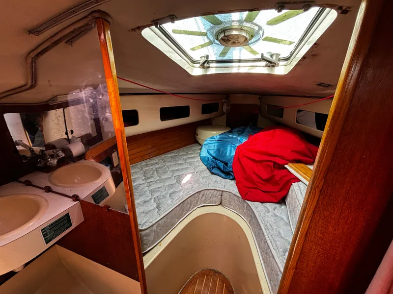 Slide: The Image of 1982 J Boats 30 interior cabin with skylight, dual sinks, and cozy sleeping area. - 13