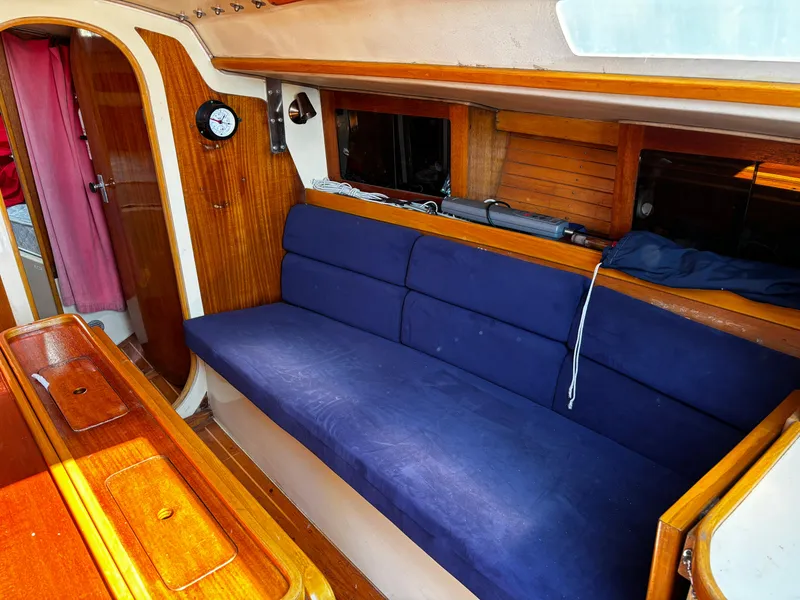 Slide: The Image of 1982 J Boats 30 interior with blue cushioned seating and wooden accents. - 9
