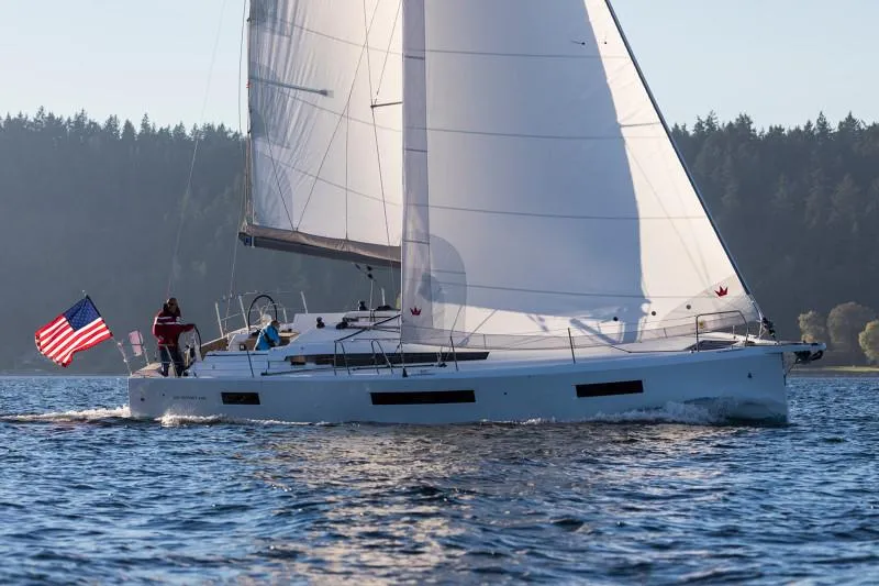 The Image of 2025 Jeanneau Sun Odyssey 440 sailing on a serene lake with an American flag. - 0