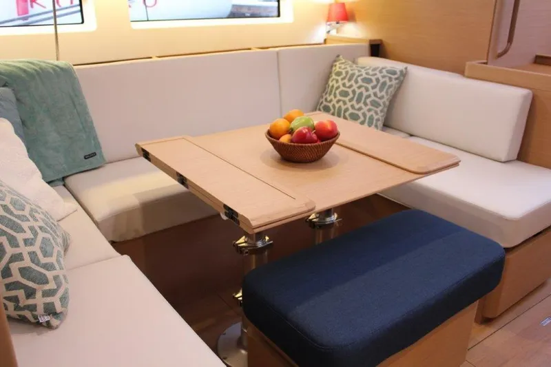 Slide: The Image of 2024 Jeanneau Sun Odyssey 490 interior with cozy seating and fruit bowl centerpiece. - 38