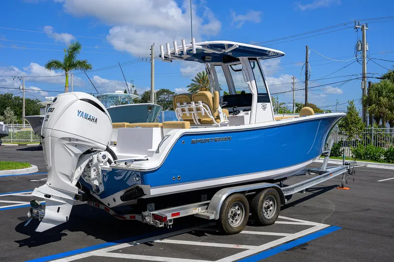 Slide: The Image of 2025 Sportsman Heritage 231 Center Console boat on trailer, blue hull, parked outdoors. - 3
