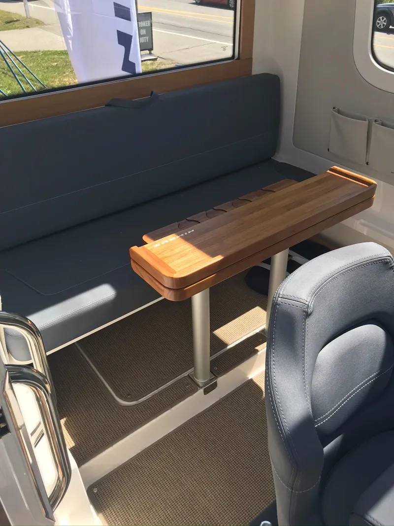 Slide: The Image of Interior of 2024 Nimbus C9 boat with wooden table and blue seating. - 21