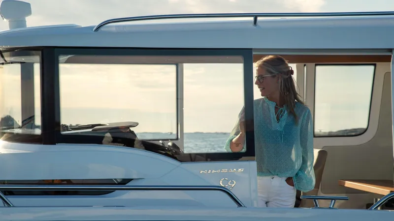 Slide: The Image of Woman on a 2024 Nimbus C9 boat, enjoying a sunny day on the water. - 6
