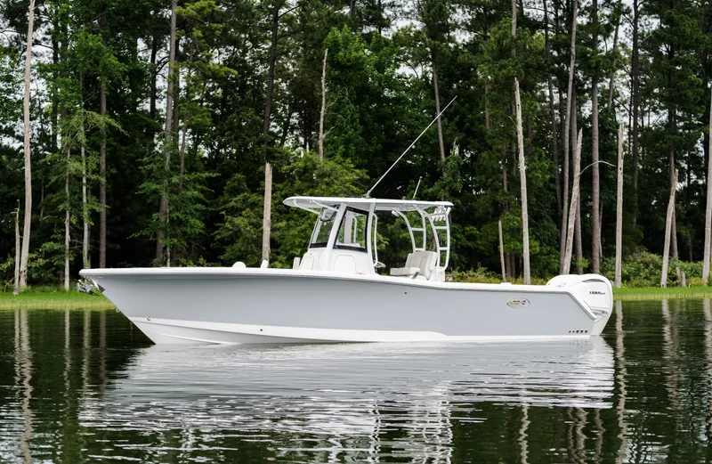 Slide: The Image of 2025 Sea Hunt Gamefish 30 boat on calm water, surrounded by trees. - 8