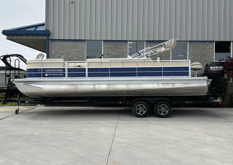 Slide: The Image of 2018 Lexington 325 Sport Tri-Toon boat on trailer, parked outside a building. - 0