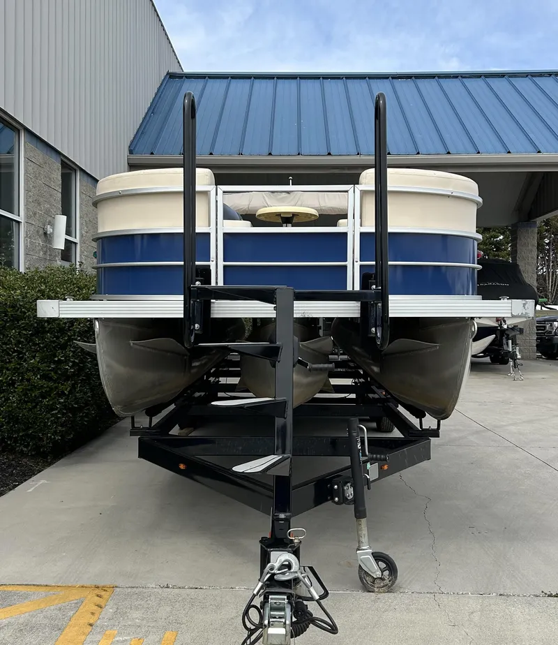Slide: The Image of 2018 Lexington 325 Sport Tri-Toon boat on trailer, parked outside building. - 2
