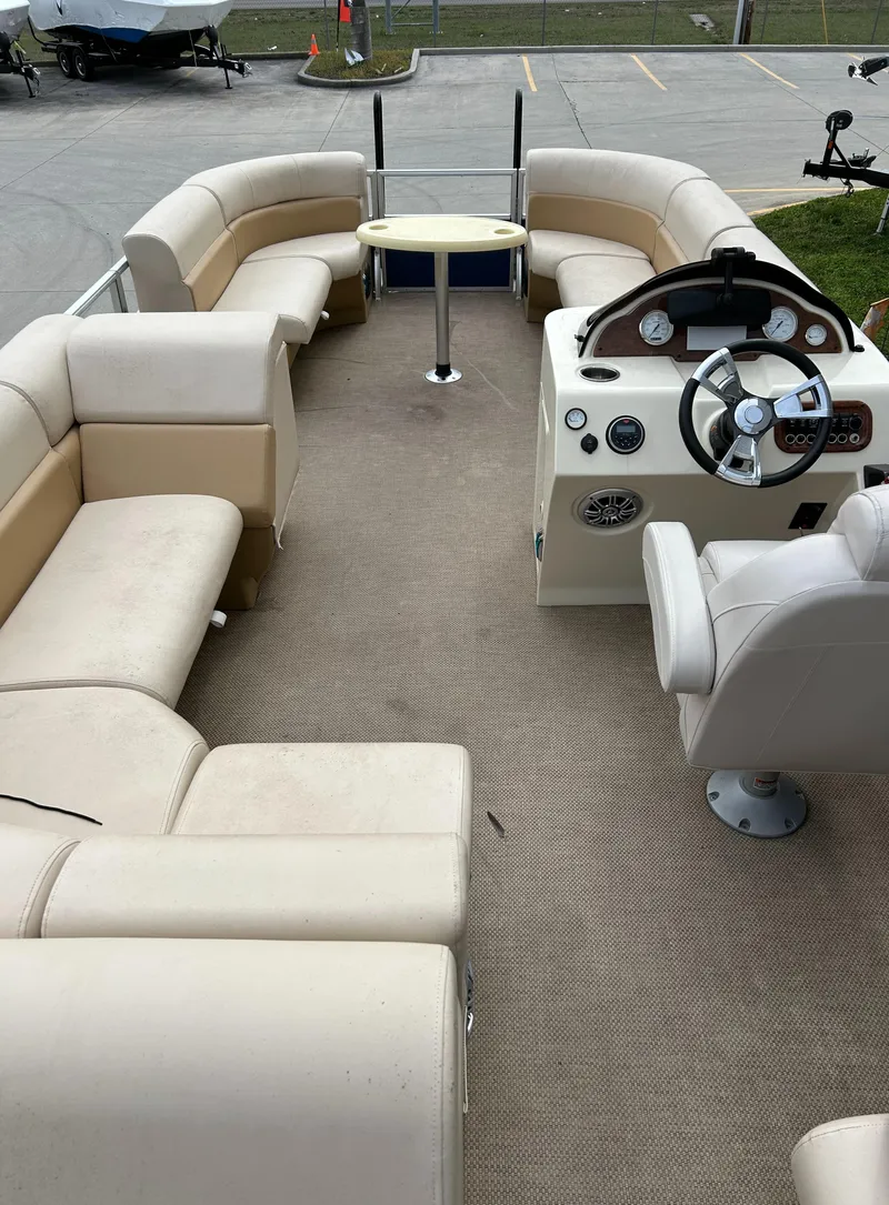 Slide: The Image of 2018 Lexington 325 Sport Tri-Toon boat interior with beige seating and steering console. - 7