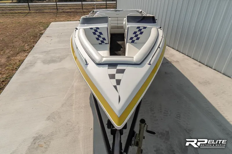 Slide: The Image of 2000 Eliminator 220 Eagle XP boat with checkered design, parked on concrete near a building. - 21