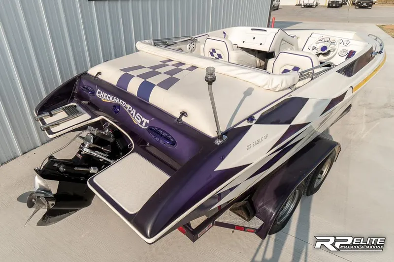 Slide: The Image of 2000 Eliminator 220 Eagle XP speedboat with checkered design, parked on trailer. - 30