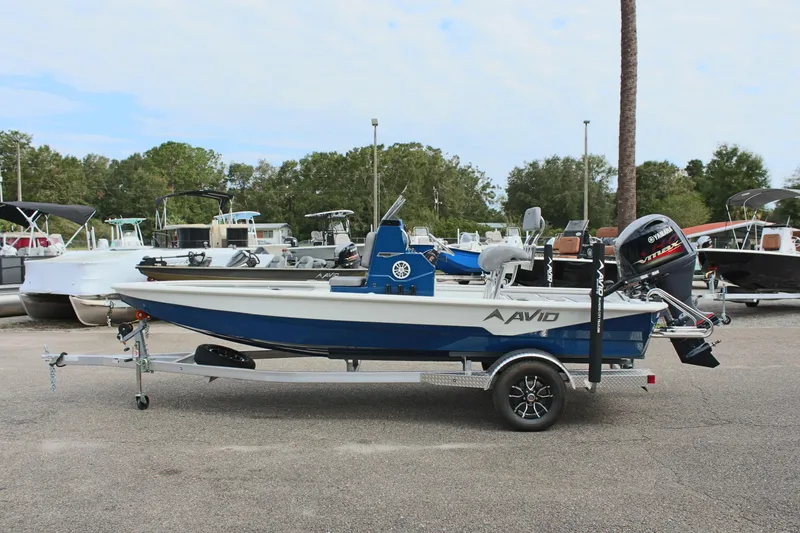 The Image of 2025 Avid 19 FSX boat on trailer, parked outdoors with other boats in the background. - 1