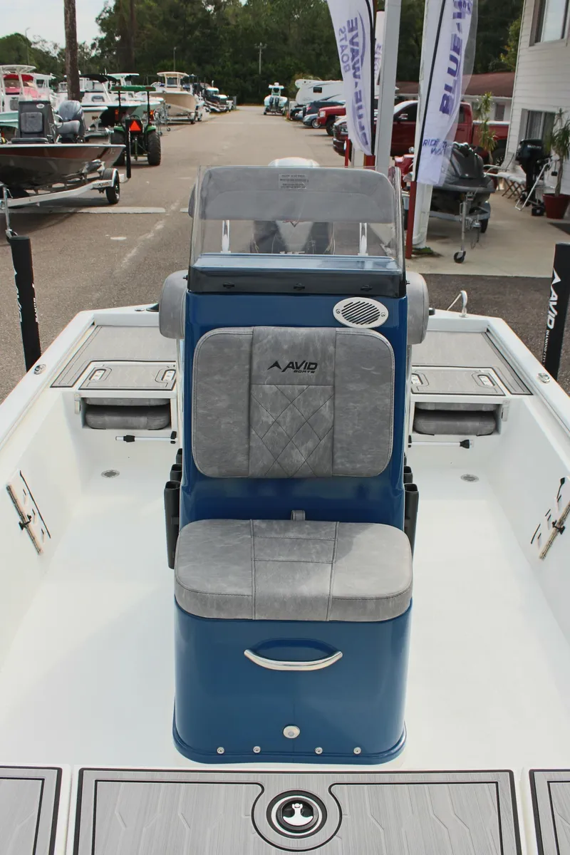Slide: The Image of 2025 Avid 19 FSX boat interior with blue and gray seating, docked at a marina. - 36