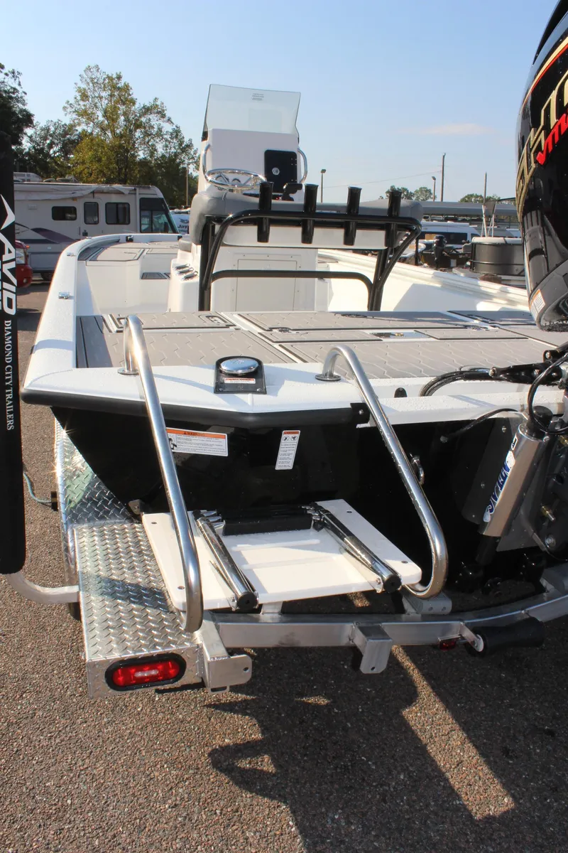 Slide: The Image of 2025 Avid 23 FSX boat, rear view with ladder and motor, parked outdoors. - 10