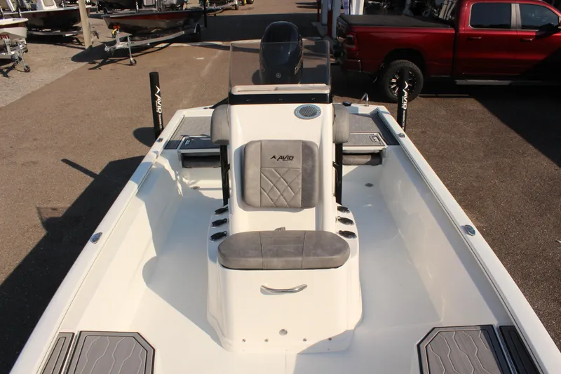 Slide: The Image of 2025 Avid 23 FSX boat interior with seating and console, parked outdoors. - 31