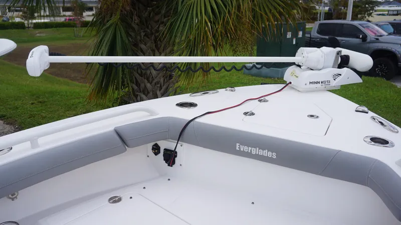Slide: The Image of 2023 Everglades 253 CC boat with Minn Kota trolling motor, docked near palm trees. - 8
