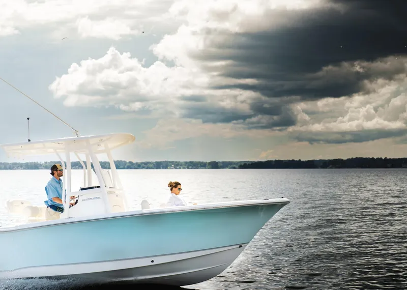 Slide: The Image of 2025 Sea Hunt Ultra 229 boat cruising on a lake under dramatic cloudy skies. - 7