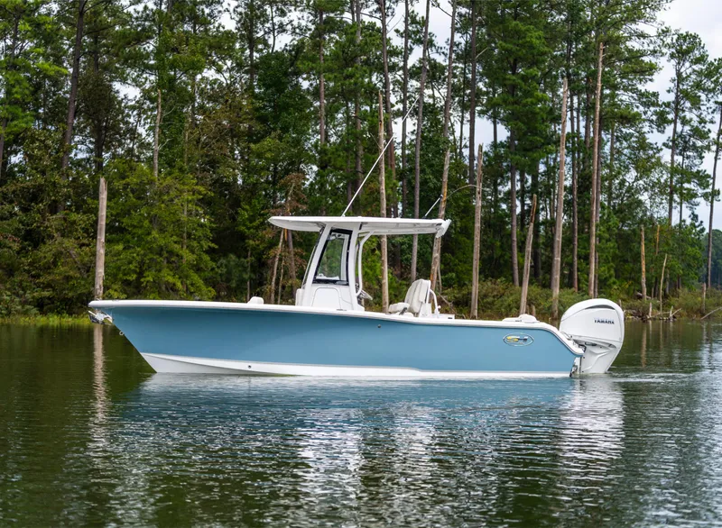 Slide: The Image of 2025 Sea Hunt Ultra 245 SE boat on a serene lake with forest backdrop. - 2