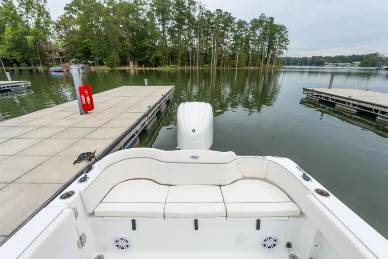 Slide: The Image of 2025 Sea Hunt Ultra 245 SE boat docked on a serene lake with lush trees. - 3