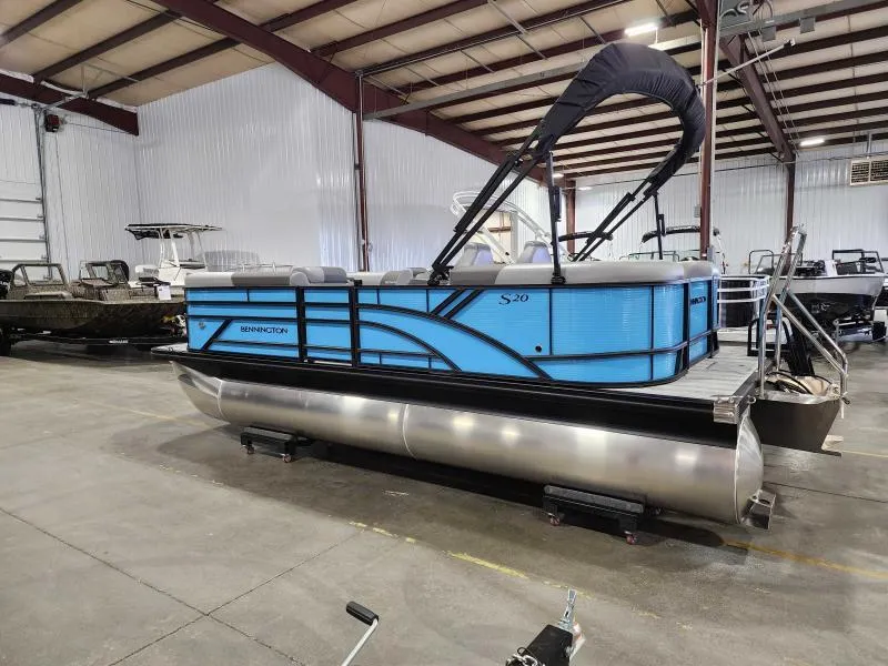 Slide: The Image of 2025 Bennington 20SSR pontoon boat in a showroom, featuring a sleek blue design. - 1
