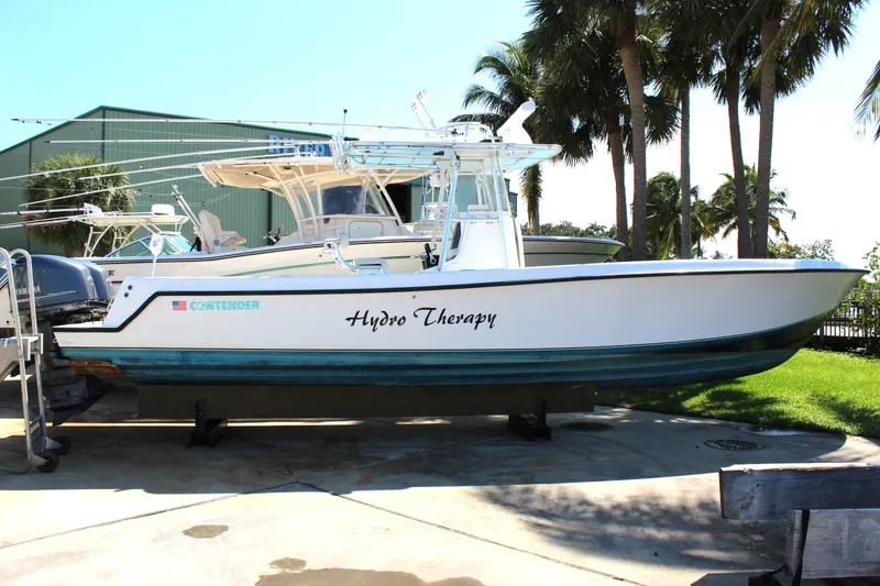 Slide: The Image of 2002 Contender 31 CC boat named "Hydro Therapy" on display near palm trees. - 33