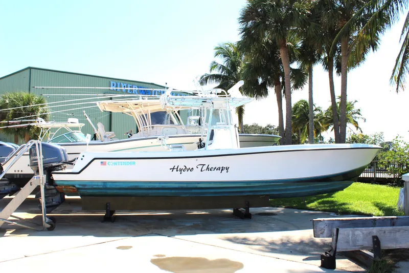 Slide: The Image of 2002 Contender 31 CC boat named "Hydro Therapy" on trailer, surrounded by palm trees. - 34