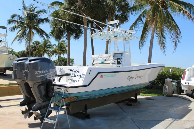 Slide: The Image of 2002 Contender 31 CC boat with dual Yamaha engines, docked under palm trees. - 10
