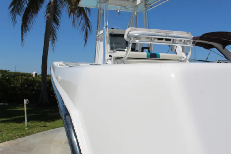 Slide: The Image of 2002 Contender 31 CC boat, white exterior, docked under clear blue sky with palm trees. - 17