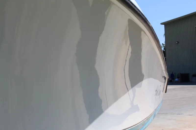 Slide: The Image of 2002 Contender 31 CC boat hull reflecting sunlight, docked near a building. - 40