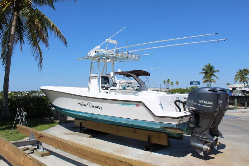 Slide: The Image of 2002 Contender 31 CC boat with Yamaha engines on a sunny day, docked near palm trees. - 41
